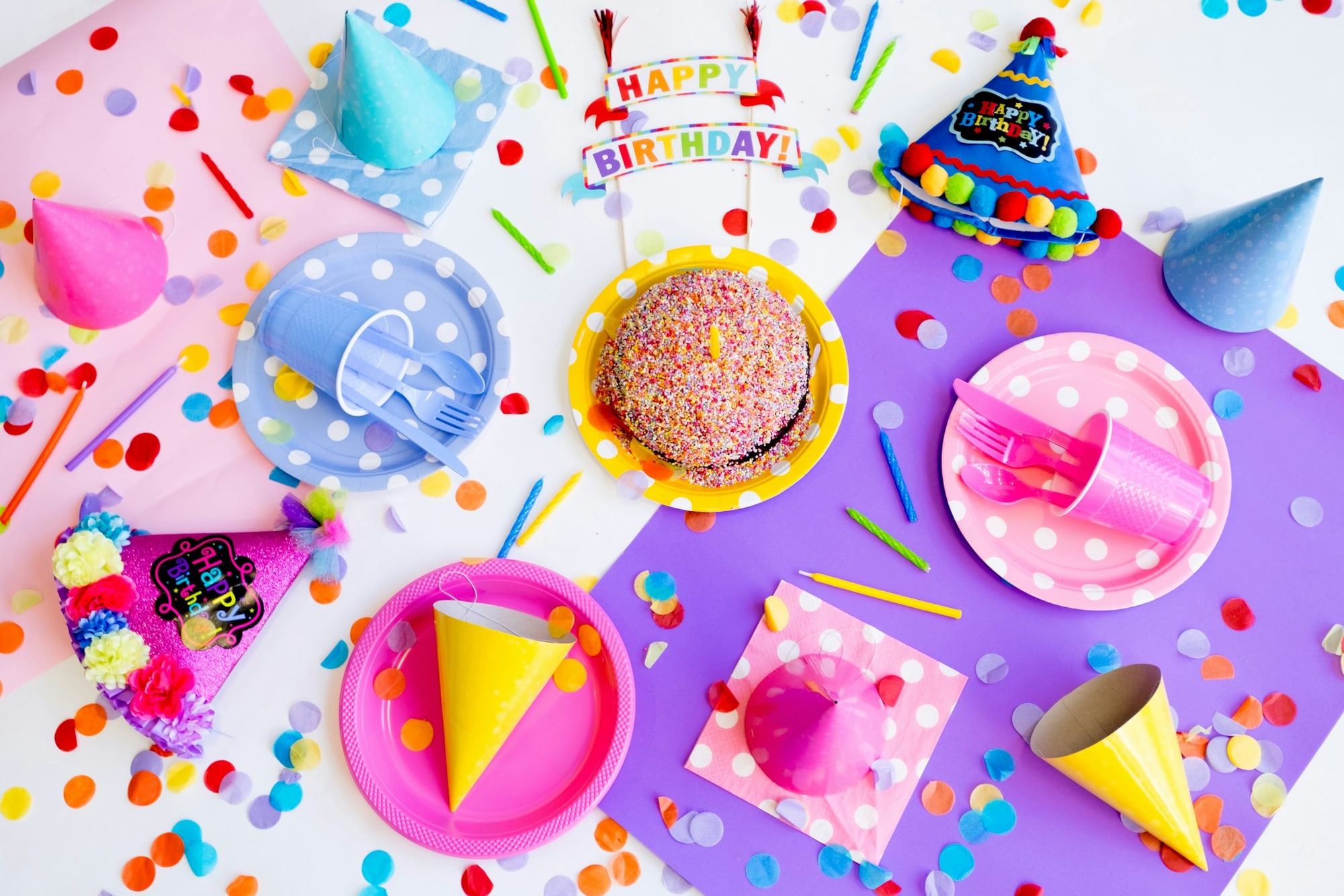 Birthday party table with hats, cake, and confetti