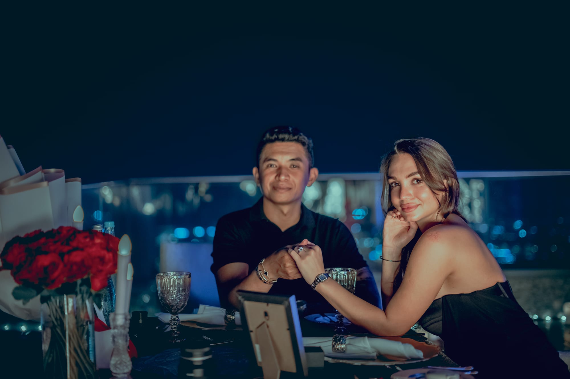 Couple seated at a candlelit proposal dinner