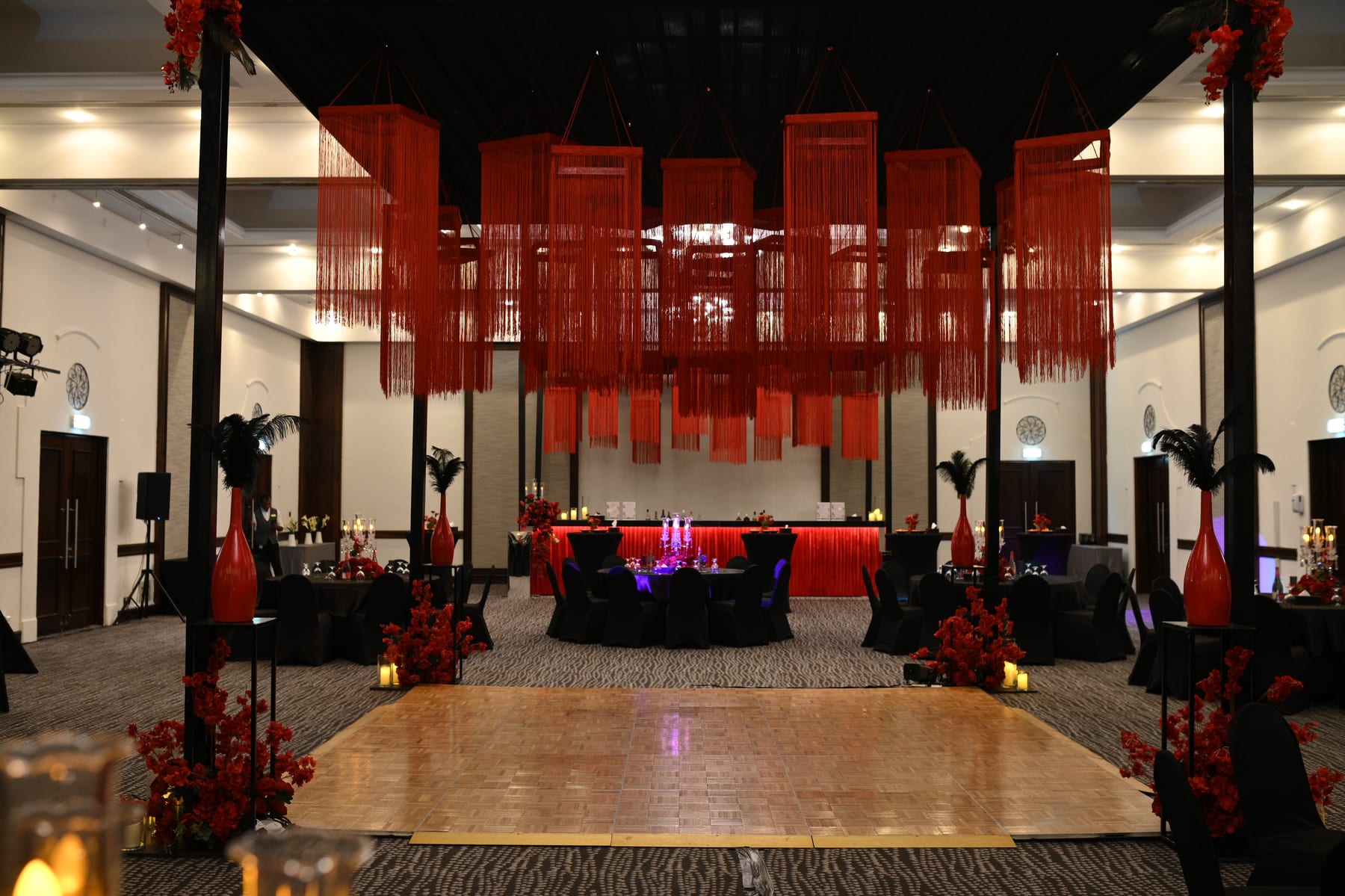 Sangeet dance floor set with red florals and a stage
