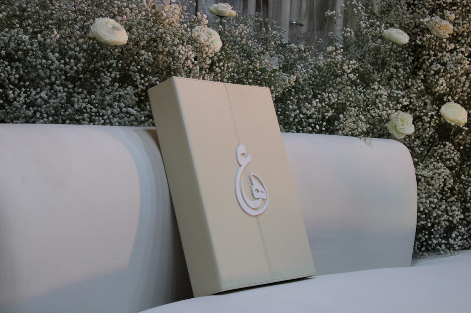 Ivory cushion with a monogram on a floral sofa