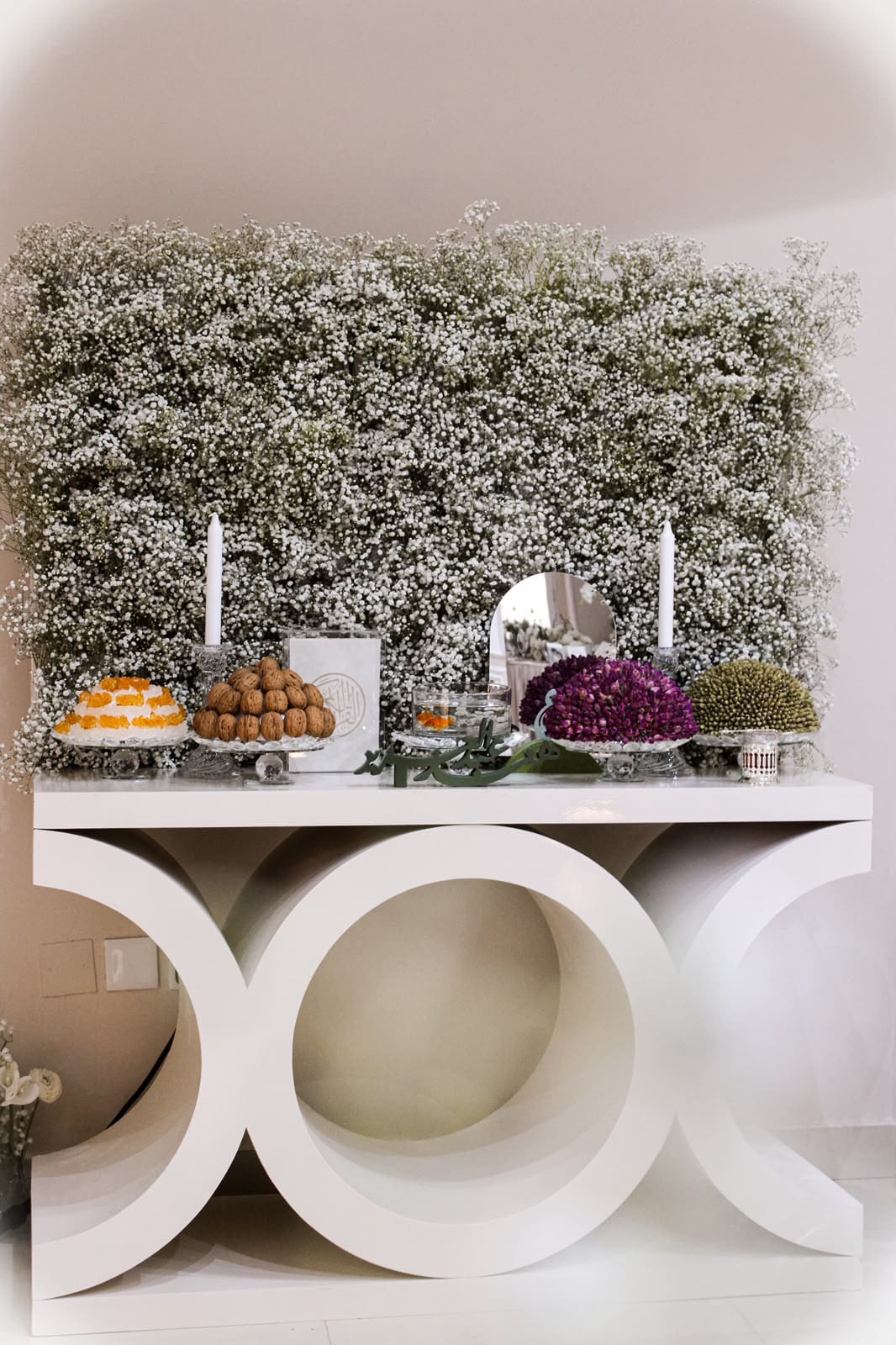 Candles set against a wall of white flowers