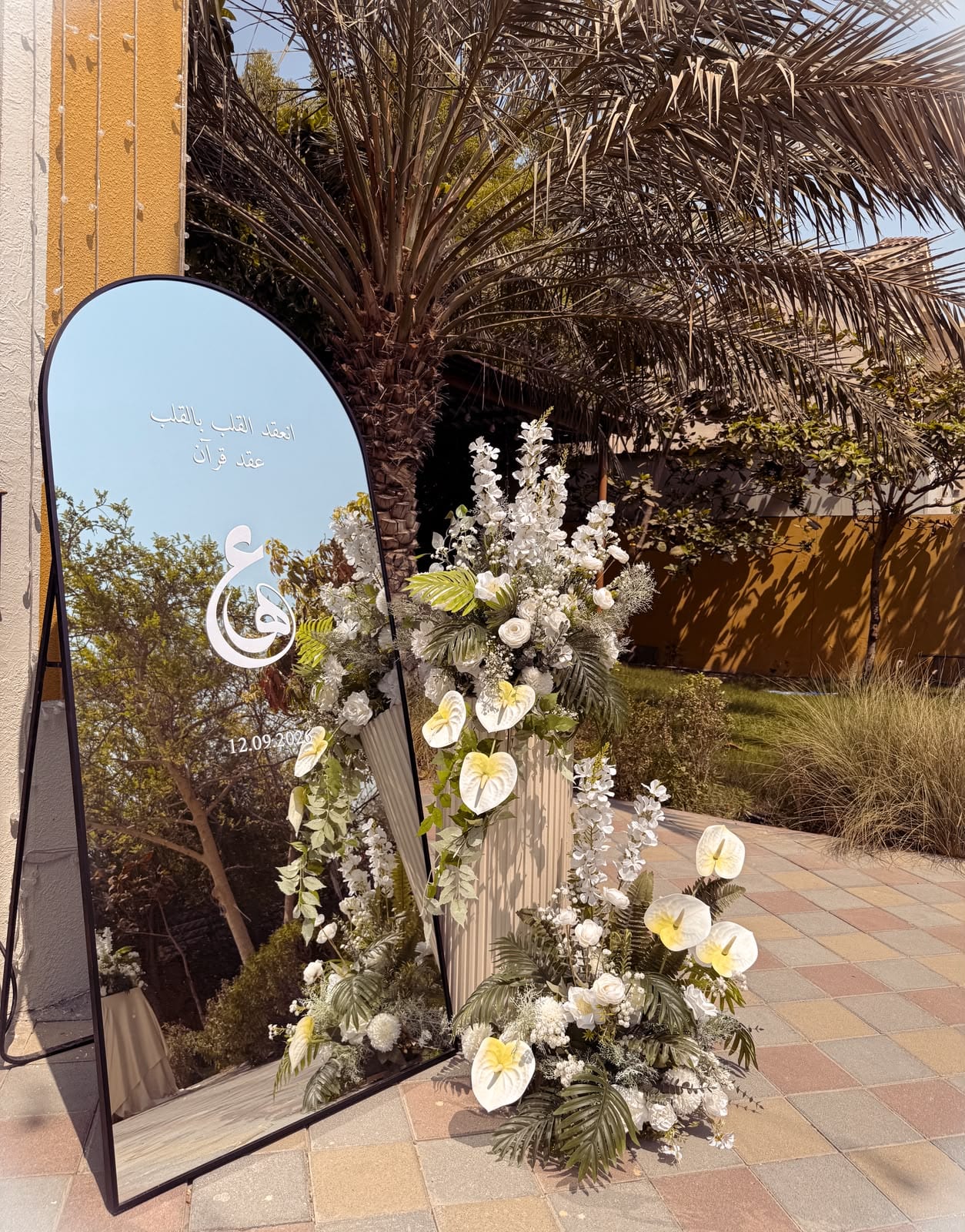 Tall mirror beside a white floral arrangement