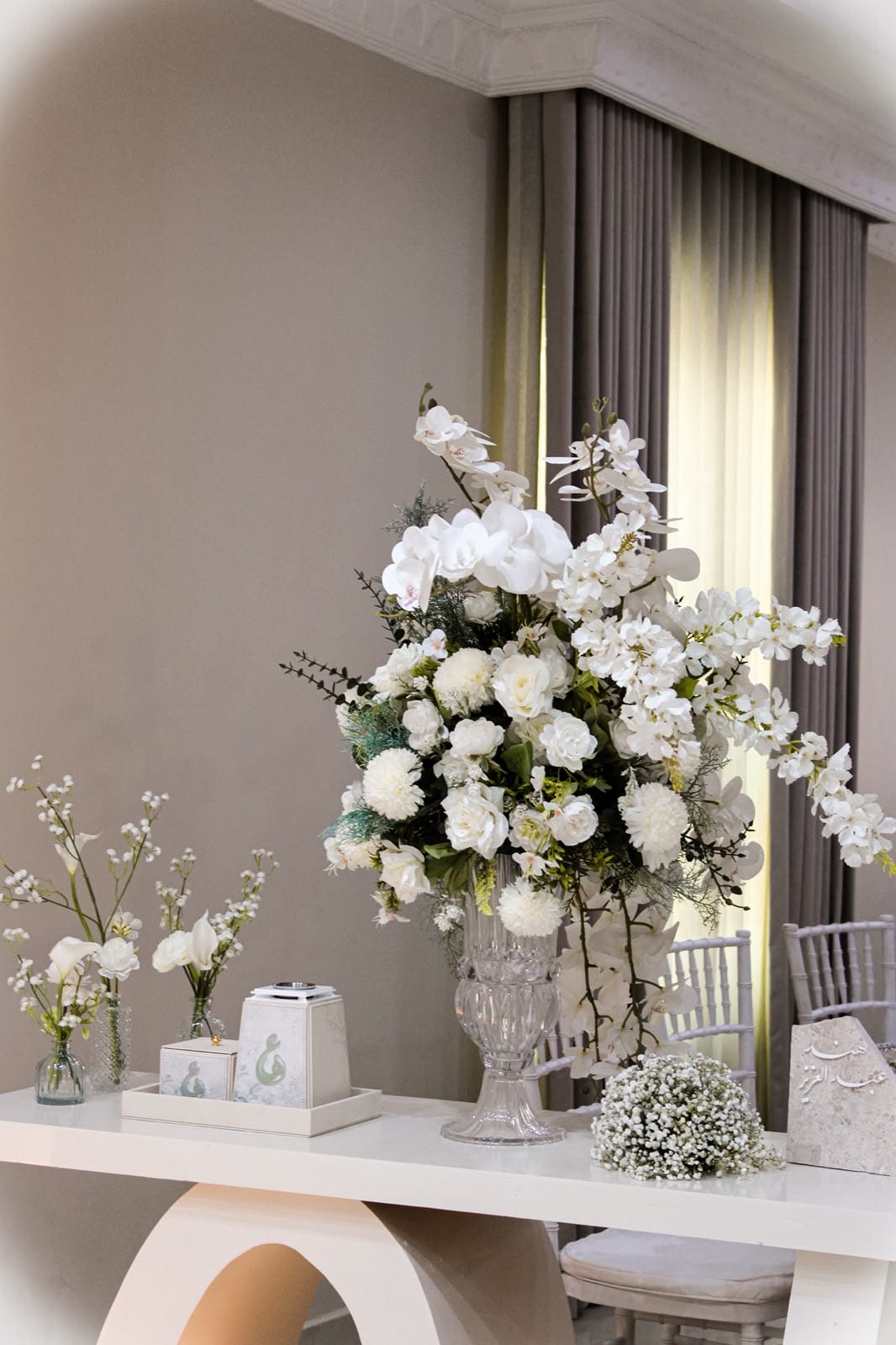 White urn of orchids and roses on a console