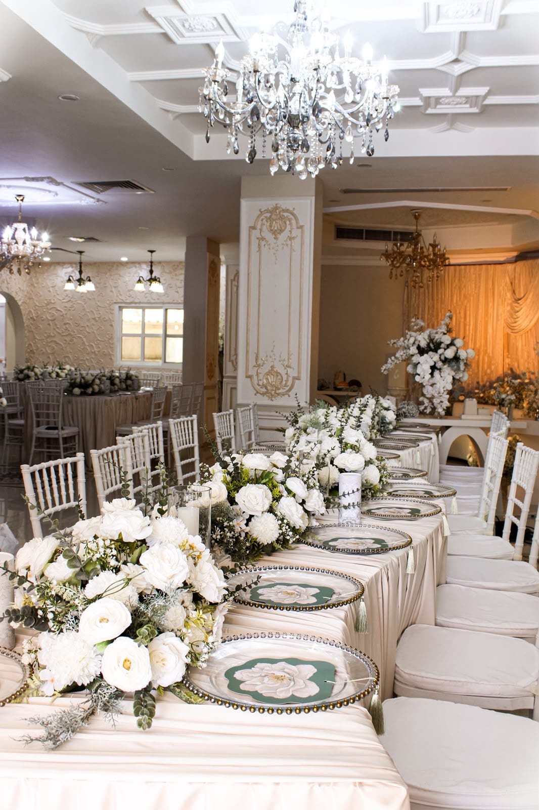 Long ivory table set with white roses and chargers